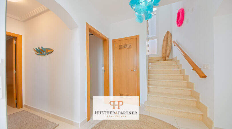 Heller Eingangsbereich mit Steintreppe, Holztüren und dekorativen Akzenten im Haus in Cala Murada.