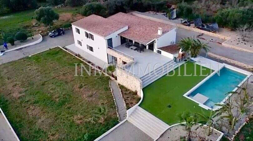 Aerial view of a white finca in Campos with terracotta roof, outdoor pool and well-maintained garden.