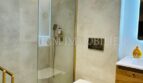 Modern designer bathroom with walk-in shower, gold accents and wall-hung toilet in Mallorca luxury apartment.