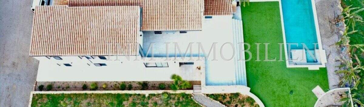 Aerial view of a finca in Campos with terracotta roof, rectangular outdoor pool, lawn and palm trees.