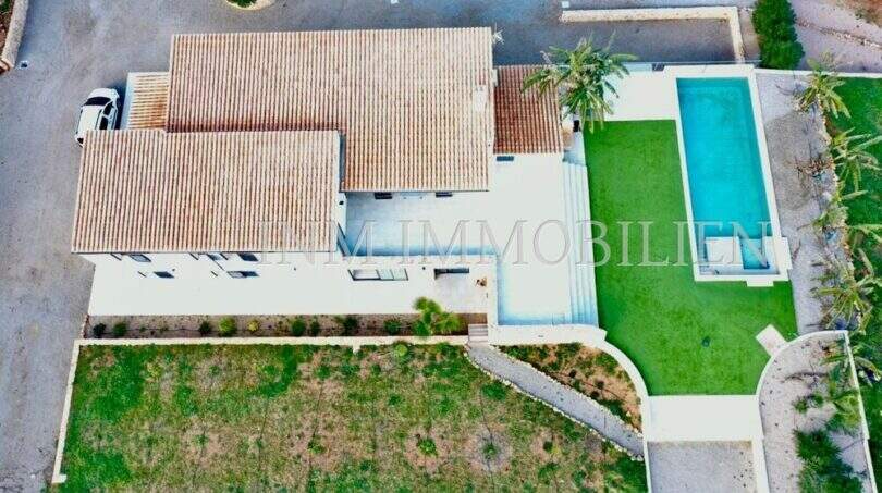Aerial view of a finca in Campos with terracotta roof, rectangular outdoor pool, lawn and palm trees.