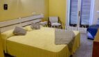 Schlafzimmer mit gelbem Doppelbett, Terrassentür mit Holzjalousien und Wandleuchte in Meereslinie-Wohnung, El Arenal