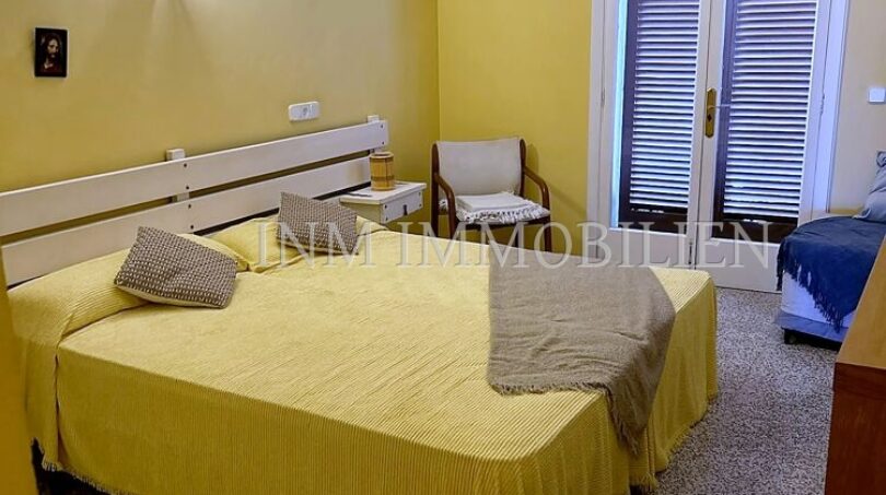 Schlafzimmer mit gelbem Doppelbett, Terrassentür mit Holzjalousien und Wandleuchte in Meereslinie-Wohnung, El Arenal