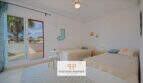 Helles Schlafzimmer mit zwei Einzelbetten, Deckenventilator und Balkon mit Palmenblick im Haus in Cala Murada.