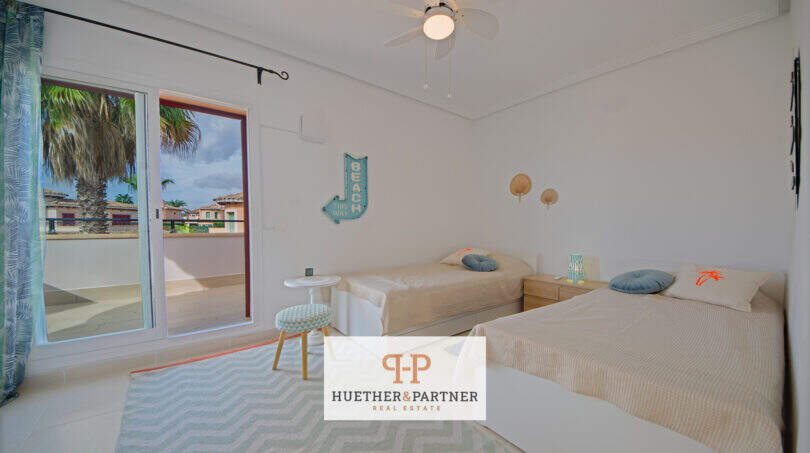 Helles Schlafzimmer mit zwei Einzelbetten, Deckenventilator und Balkon mit Palmenblick im Haus in Cala Murada.