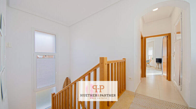 Heller Treppenaufgang mit Holzgeländer und weißen Wänden im Haus in Cala Murada