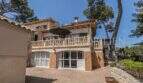 Außenansicht der Villa in Marratxí mit Terrasse, Balkon, Sonnenschirm und gepflastertem Innenhof, umgeben von Pinien.
