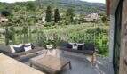 Terraza cubierta de la finca en Sóller con muebles lounge y vista a jardines escalonados y montañas boscosas.