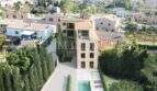 Vista aérea de una finca de piedra natural en Sóller con piscina, jardín y edificios de pueblo circundantes.
