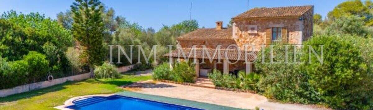Finca near Campos: stone house with blue pool, loungers and lush greenery under blue sky.