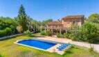 Finca near Campos: stone house with blue pool, loungers and lush greenery under blue sky.