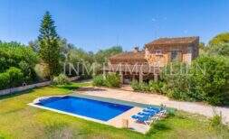 Finca near Campos: stone house with blue pool, loungers and lush greenery under blue sky.