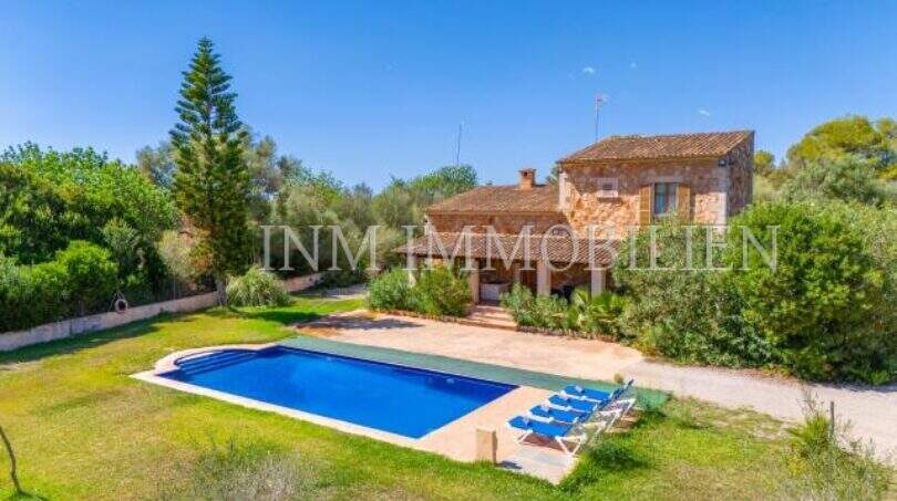 Finca near Campos: stone house with blue pool, loungers and lush greenery under blue sky.