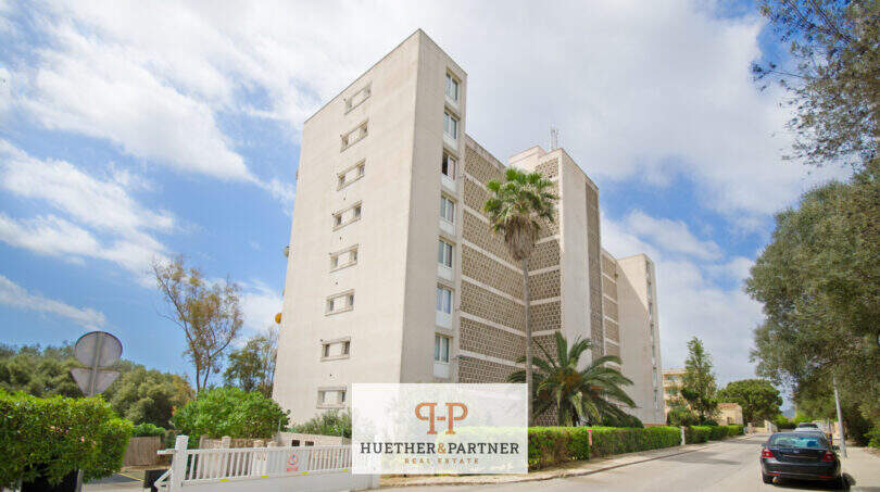 Außenansicht eines mehrstöckigen Apartmentgebäudes in Cales de Mallorca, umgeben von Palmen und mediterraner Vegetation.
