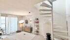Helles Wohnzimmer der Maisonette mit weißer Wendeltreppe, modernem Sideboard und großer Terrassentür in Son Armadans