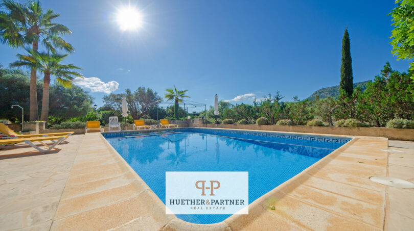 Gran piscina exterior de la finca Felanitx con tumbonas, palmeras y vistas a Sant Salvador