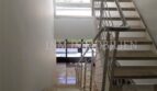 Moderno hueco de escalera con barandilla metálica y gran ventana en el ático Bendinat