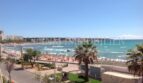 Panoramablick vom Balkon auf den belebten Strand von El Arenal mit türkisblauem Meer und Palmen.