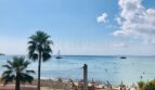 Strandpromenade El Arenal mit türkisblauem Meer, Palmen, Strandbar und Segelboot – Blick aus der Wohnung in erster Meereslinie.