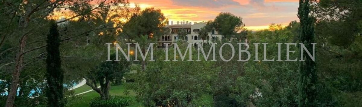 Garden area with Mediterranean vegetation and view of penthouse complex in Bendinat at sunset.