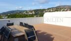 Spacious roof terrace with wooden deck, dining table and mountain view of the penthouse apartment in Bendinat