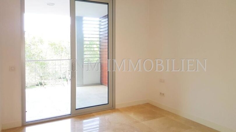 Bright, empty room with marble floor and sliding glass door to the balcony in modern penthouse Bendinat