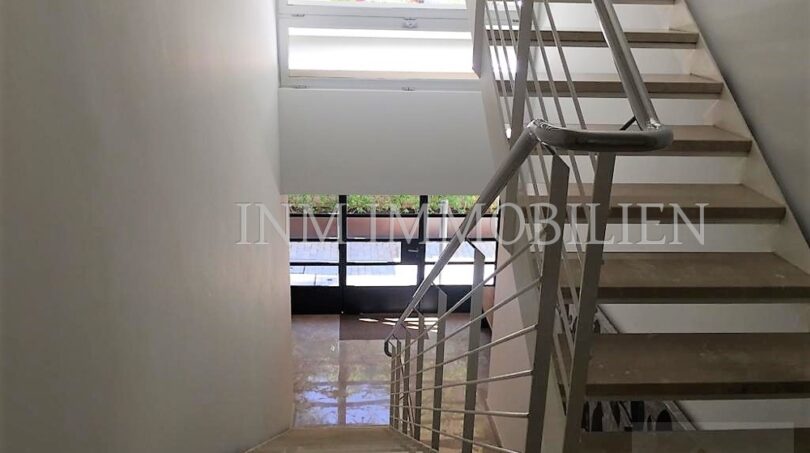 Bright stairwell with modern metal railing and large windows in penthouse Bendinat