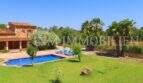 Finca near Campos: exterior view with pool, loungers, green lawn and palms under blue sky.