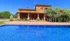 Finca near Campos: rustic stone house with large blue pool and blooming tree in well-maintained garden.