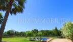 Spacious garden of the finca near Campos with pool, palms and lush vegetation under blue sky.