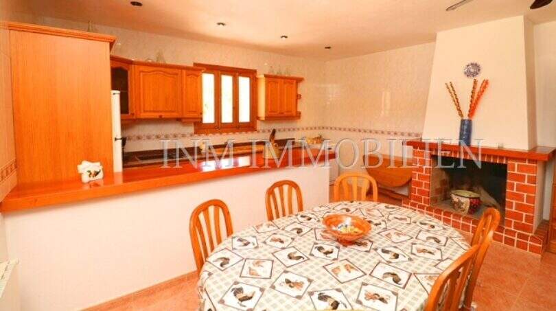 Spacious kitchen with dining area, wooden furniture, fireplace and kitchen unit of the finca near Campos with pool.