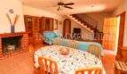 Living-dining room of Finca Campos with dining table, fireplace, wooden furniture and staircase to upper floor.