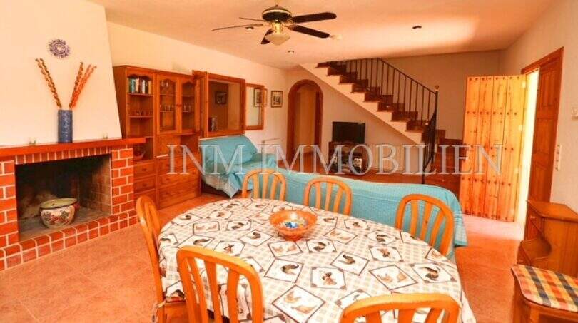 Living-dining room of Finca Campos with dining table, fireplace, wooden furniture and staircase to upper floor.