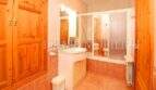 Bright bathroom of the finca near Campos with shower, sink and wooden cabinets in warm tones.