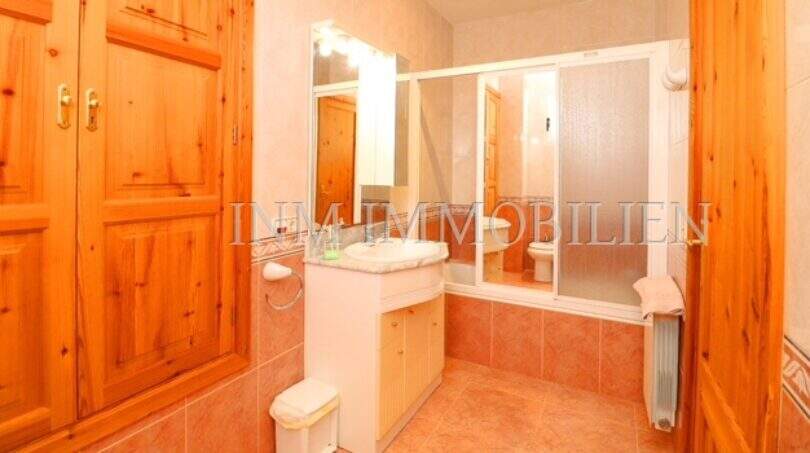 Bright bathroom of the finca near Campos with shower, sink and wooden cabinets in warm tones.
