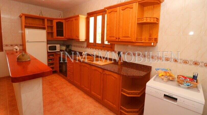 Spacious kitchen of Finca Campos with wooden cabinets, granite worktop and dishwasher