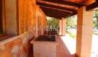 Covered terrace of the finca near Campos with barbecue station, wooden ceiling and natural stone wall.