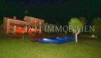 Finca Campos at night: illuminated pool, well-maintained lawn and rustic stone house with warm lighting.