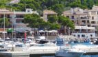 Hafen von Cala Ratjada mit Booten, Restaurants und mediterranen Gebäuden direkt am Wasser auf Mallorca.