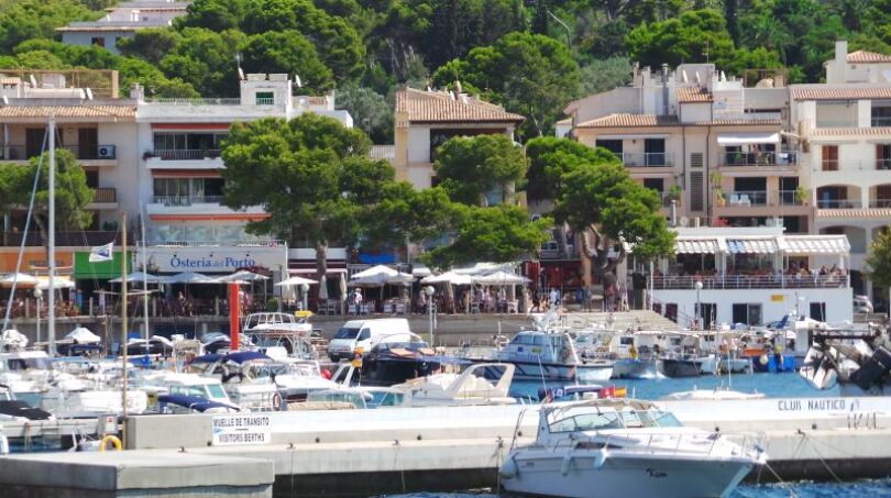 Hafen von Cala Ratjada mit Booten, Restaurants und mediterranen Gebäuden direkt am Wasser auf Mallorca.