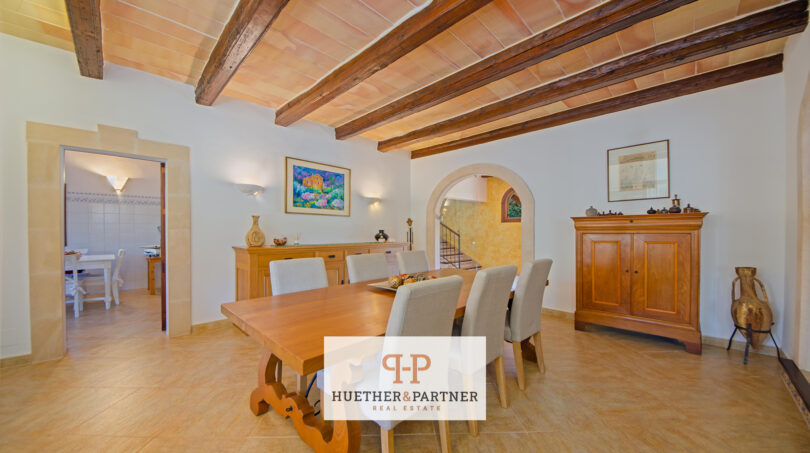 Helles Esszimmer der Finca Felanitx mit Holzbalkendecke, Natursteinboden und rustikalem Esstisch.