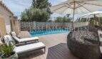 Sonnige Poolterrasse mit Holzdeck, Liegestühlen und Rattansessel der Villa in Marratxí