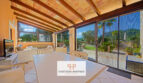 Terraza cubierta de la finca Felanitx con techo de vigas de madera, mesa de comedor y vistas a la piscina y Sant Salvador.