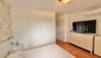 Helles Schlafzimmer mit Doppelbett, weißer Kommode, Flachbild-TV und Terrakottaboden im Reiheneckhaus Pollença