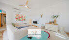 Helles Wohnzimmer mit Deckenventilator, Klimaanlage, Sofa, TV und tropischem Flamingo-Bild in Haus Cala Murada