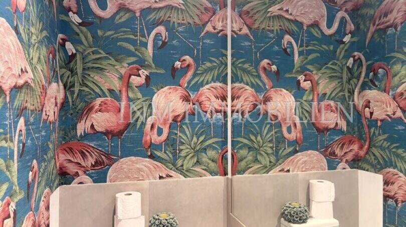 Gäste-WC mit auffälliger Flamingo-Tapete in Blau-Rosa, weißem WC und Spiegel in Maisonette-Dachgeschosswohnung Palma