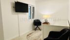 Modern living room of the designer apartment in Palma with black designer chairs, flat-screen TV and stylish ceiling lamp.
