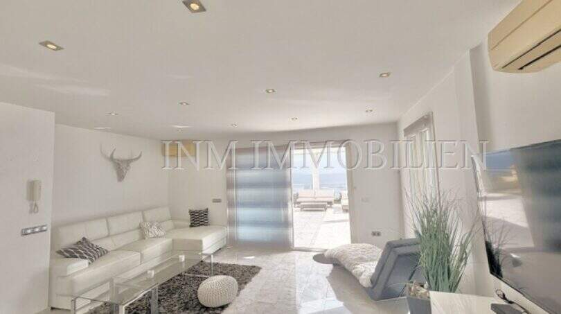 Helles Wohnzimmer mit weißer Ledercouch, Glastisch und Zugang zur Terrasse mit Meerblick in Cala Pi