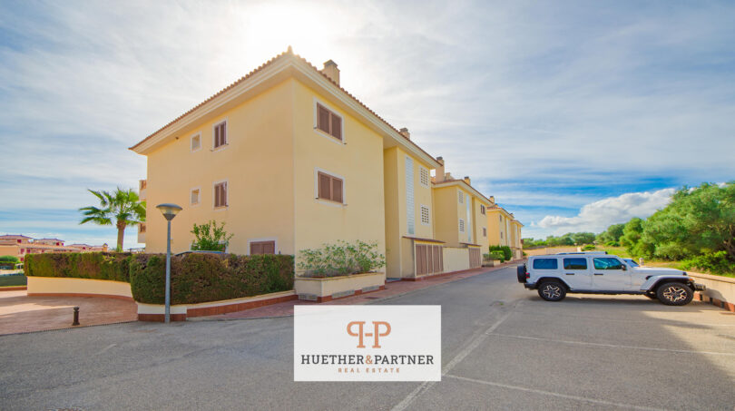 Außenansicht eines gelben Mehrfamilienhauses in Cales de Mallorca mit gepflegter Grünanlage und ruhiger Wohnstraße.