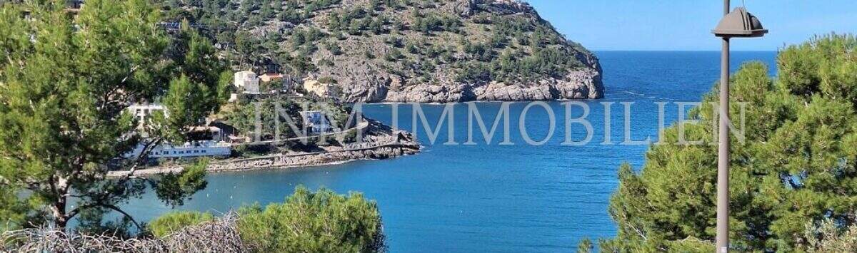 Panoramablick auf die Bucht von Port de Sóller mit Leuchtturm, türkisblauem Meer und bewaldeter Halbinsel